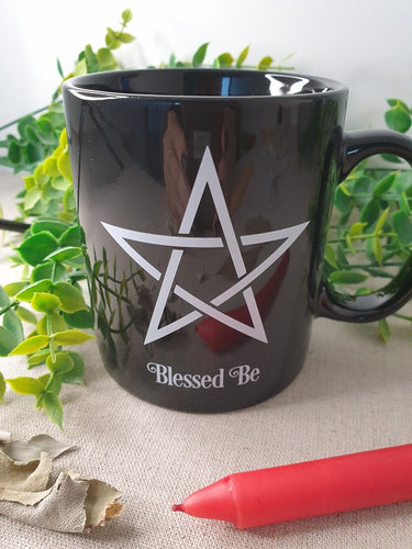 Black Blessed Be Mug near red candle and leaf