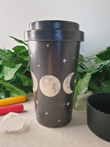 Black Triple Moon Bamboo Travel Mug with rubber sleeve near candle and crystals